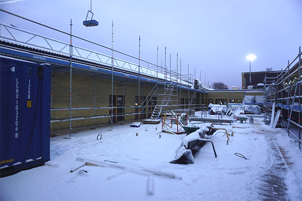 Snötäckt innergård med byggmaterial på
