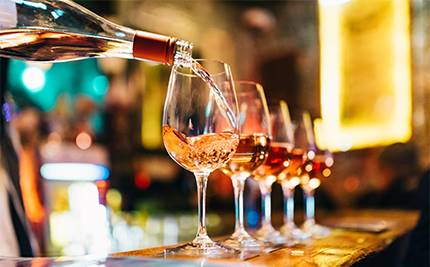Vinglas på rad fylls på med vin från flaska