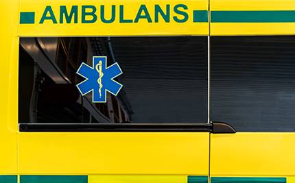 Fönster på ambulans, gul bakgrund med grön text: AMBULANS