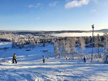 Valfjället skicenter, en solig dag. Vy från uppe i backen, slalomåkare syns i bilden.