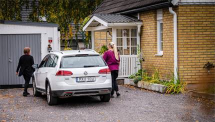 personal med hus i bakgrunden